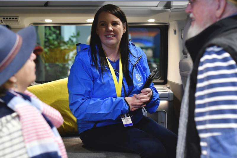 A VW representative sitting inside a VW camper chatting to a couple of show attendees. 