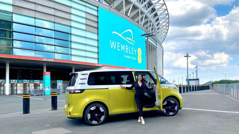 Photo of Gina Buckley standing next to an ID Buzz parked outside Wembley Stadium. 
