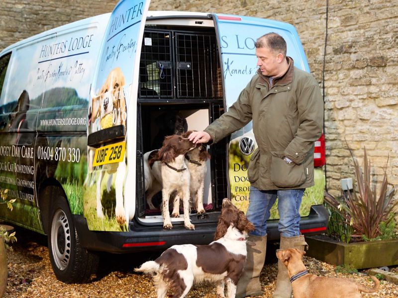 Richard the owner Hunters Lodge Doggy Daycare unloading dogs from the back of a VW van.