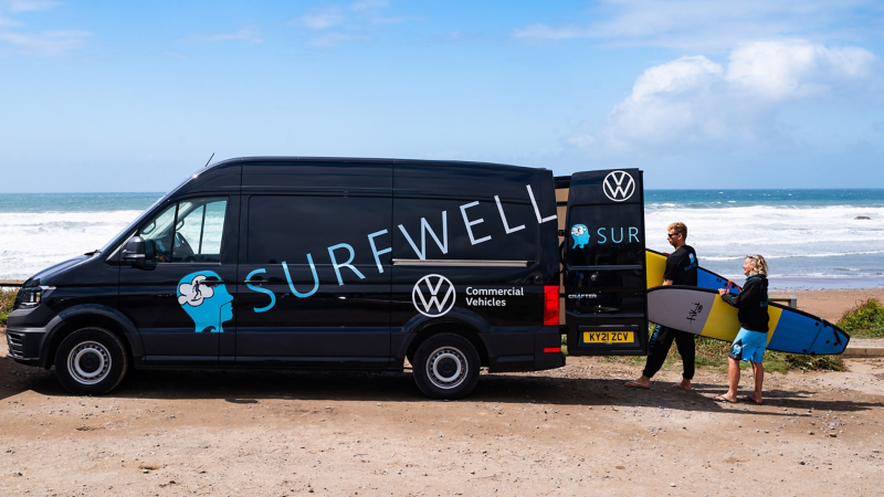 Surfwell team members loading surfboards into a VW van. 