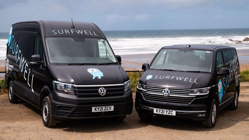 A photo of two Surfwell branded VW vans. 