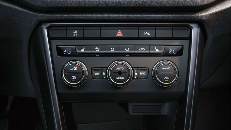 Tableau de bord d'une voiture, montrant les commandes de climatisation et de chauffage, avec des boutons rotatifs pour la température, des boutons pour les réglages de ventilation et de dégivrage, ainsi que des boutons pour les fonctionnalités de sécurité comme le warning et le Park Assist.