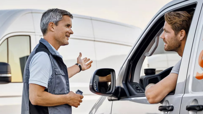 Conductor y técnico de Volkswagen charlando sobre el mejor tipo de aceite para los automóviles
