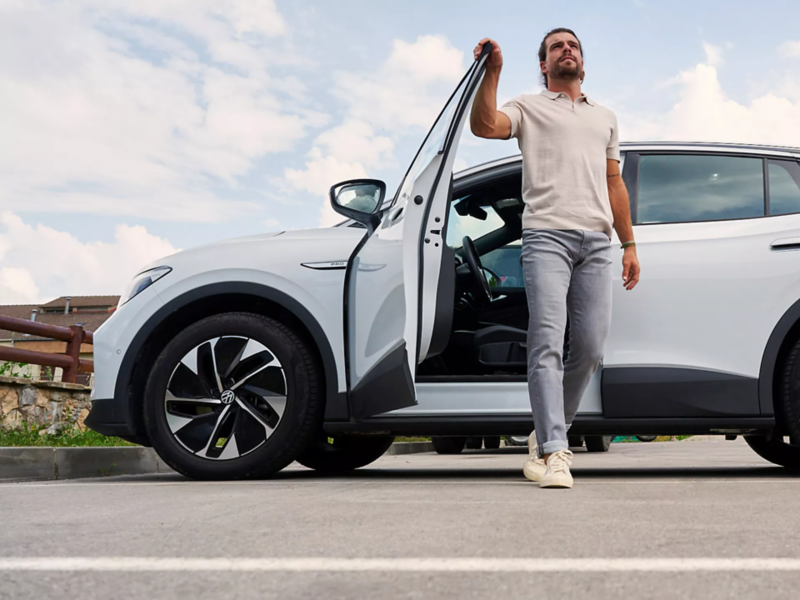 Man stapt uit witte Volkswagen ID.4 op een bewolkte zomerse dag