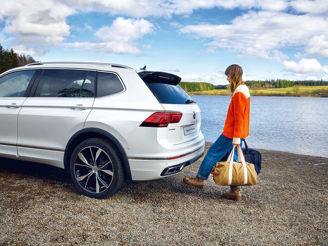 woman packing VW Tiguan Allspace with lake in the background