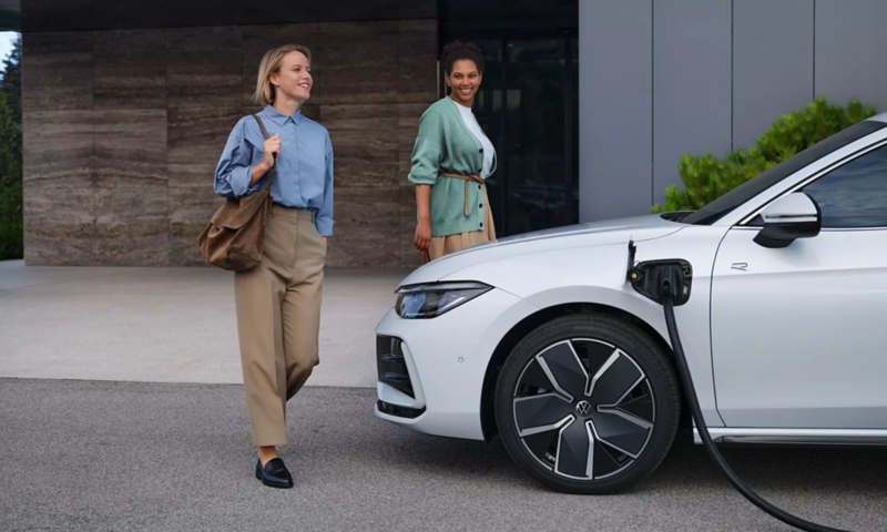 Vriendinnen lopen bij een witte Passat Plug-In hybride