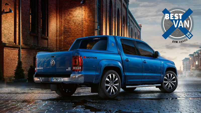 Der Amarok im Halbprofil von hinten vor einem rustikalem Lagerhaus.