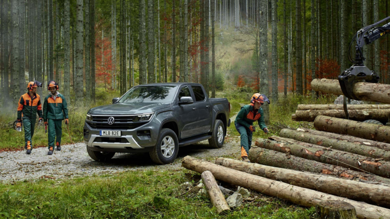 En grå VW Amarok Life pickup i skogen omgiven av skogsarbetare