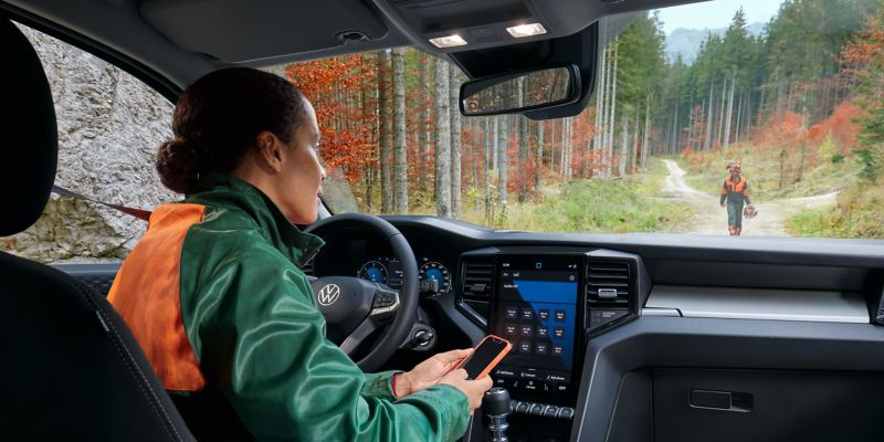Una donna a bordo del pick-up Nuovo Amarok Volkswagen tiene il cellulare in mano.