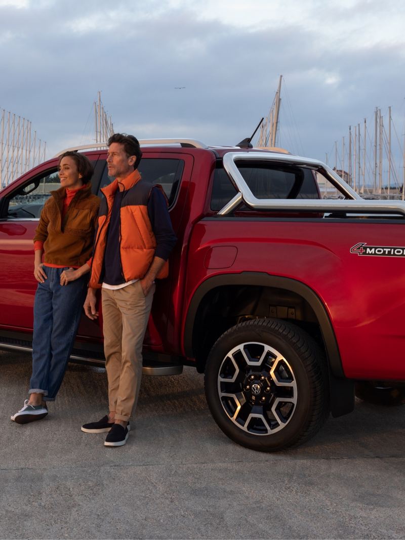 Two people are leaning on the side of an Amarok.