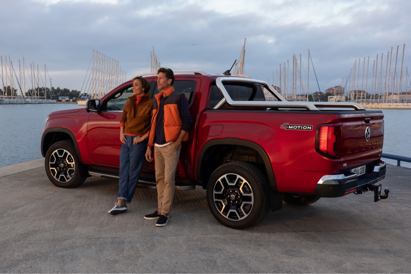 Two people are leaning on the side of an Amarok.