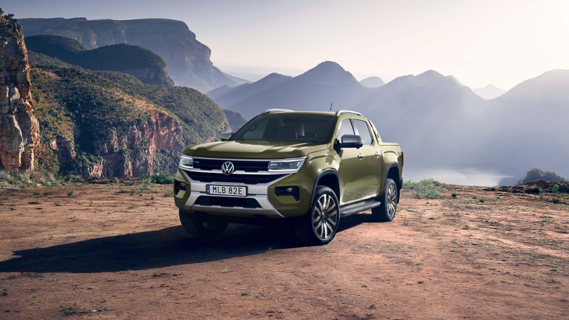 En grön VW Amarok Aventura pickup parkerad på en grusplan med berg i bakgrunden