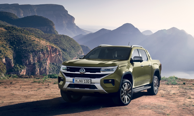 Ein VW Amarok parkt vor einer bergigen Landschaft in der Sonne.