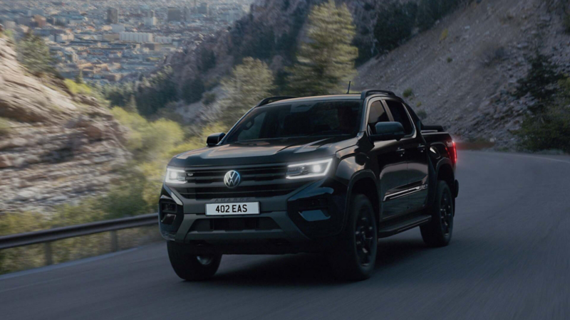 the new Amarok Dark Label driving along a country road with mountains in the background
