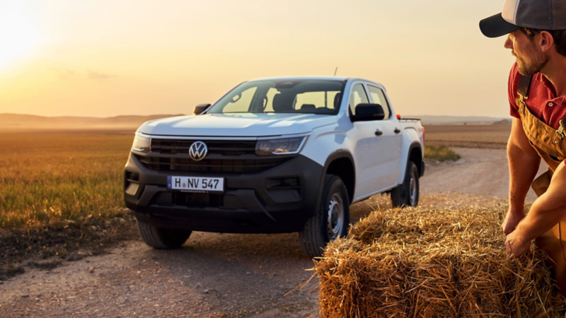 Una Amarok de ocasión aparcada en un atardecer campestre mientras una persona carga paja cerca de ella