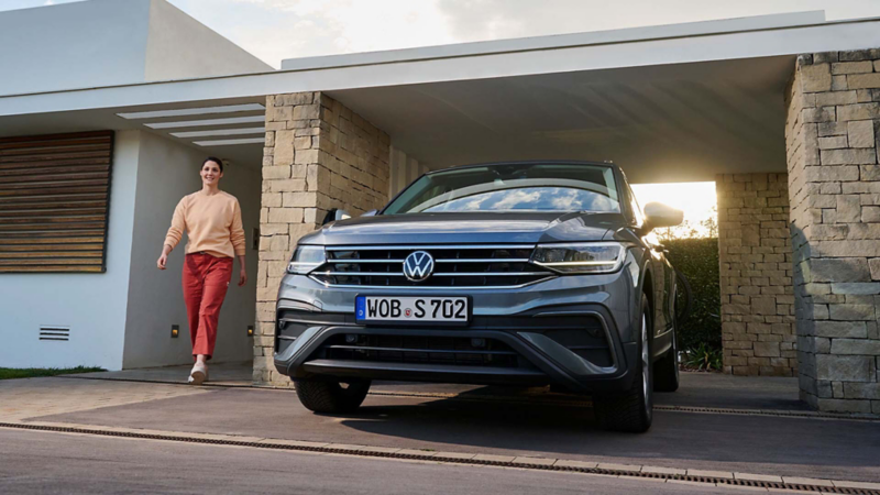 Una persona junto a un Volkswagen Tiguan Allspace aparcado en una casa