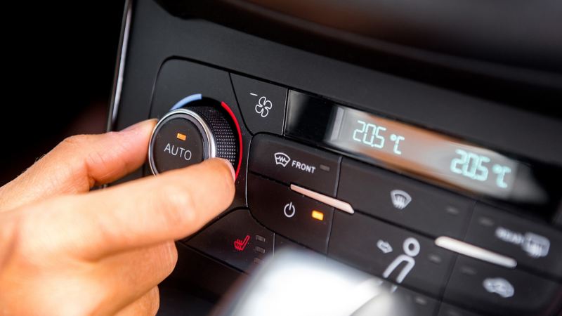 Die Armatur eines Elektroautos ist zu sehen, an der eine Person am linken Rad die Temperatur einstellt.