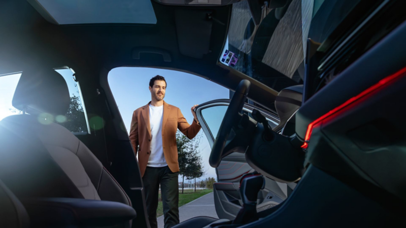 Conductor de auto Volkswagen abre la puerta para ingresar. 