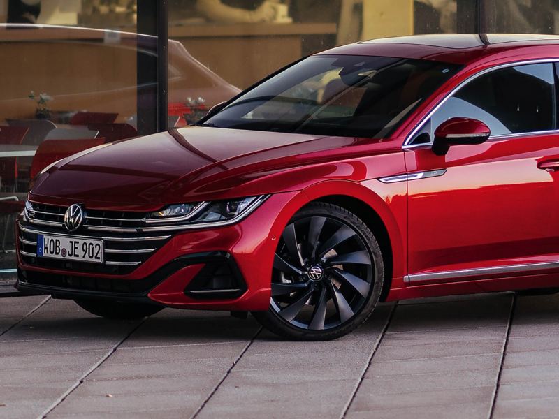 Woman standing next to a red VW Arteon Shooting Brake