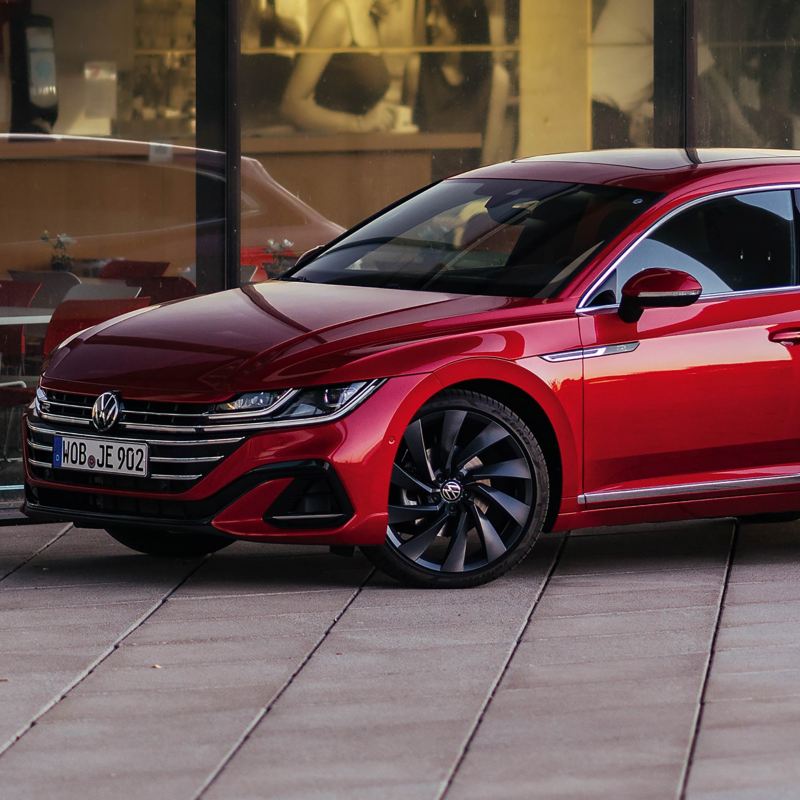 Woman standing next to a red VW Arteon Shooting Brake