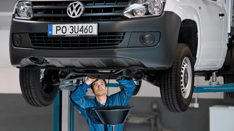 Pracownik serwisu wymienia olej silnikowy w dostawczym Volkswagenie.