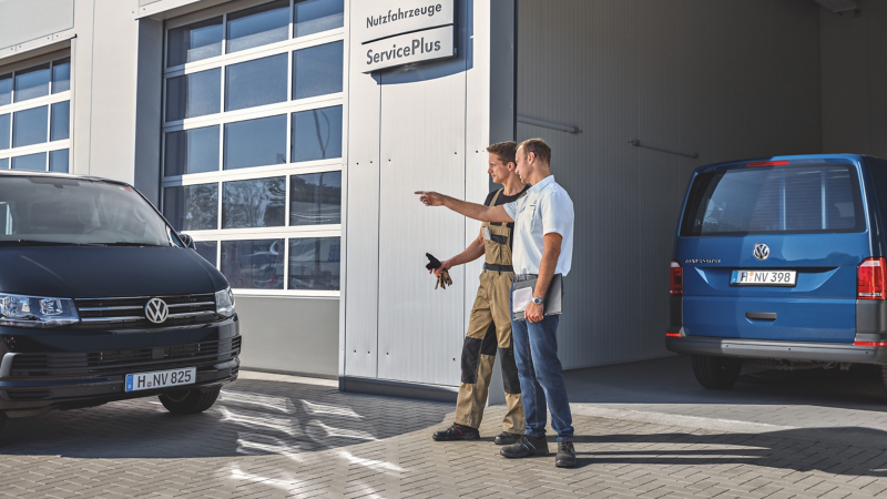 to medarbejdere på et volkswagen erhvervscenter står og kigger på en transporter