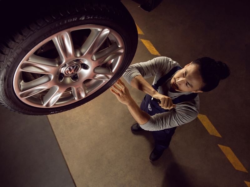 Un addetto Volkswagen ispeziona la ruota di un veicolo.