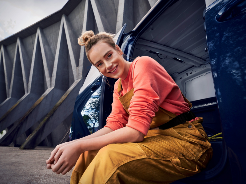 En hantverkare sitter i dörröppningen på en VW. ID. Buzz Cargo.