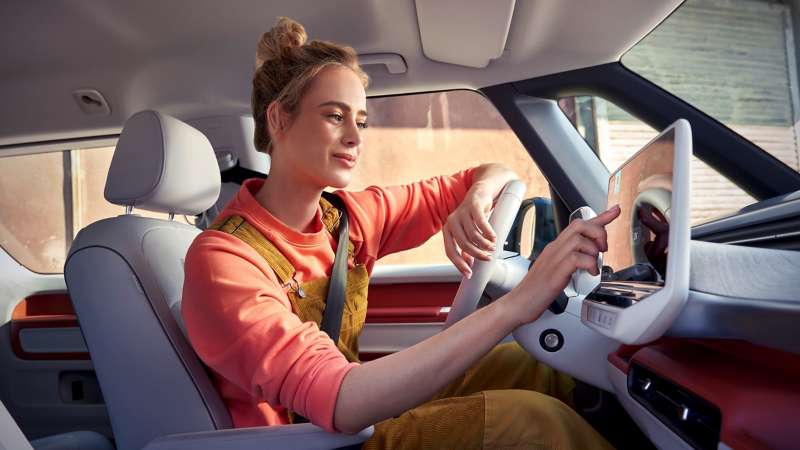A woman operates the multifunction display of a VW ID. Buzz.