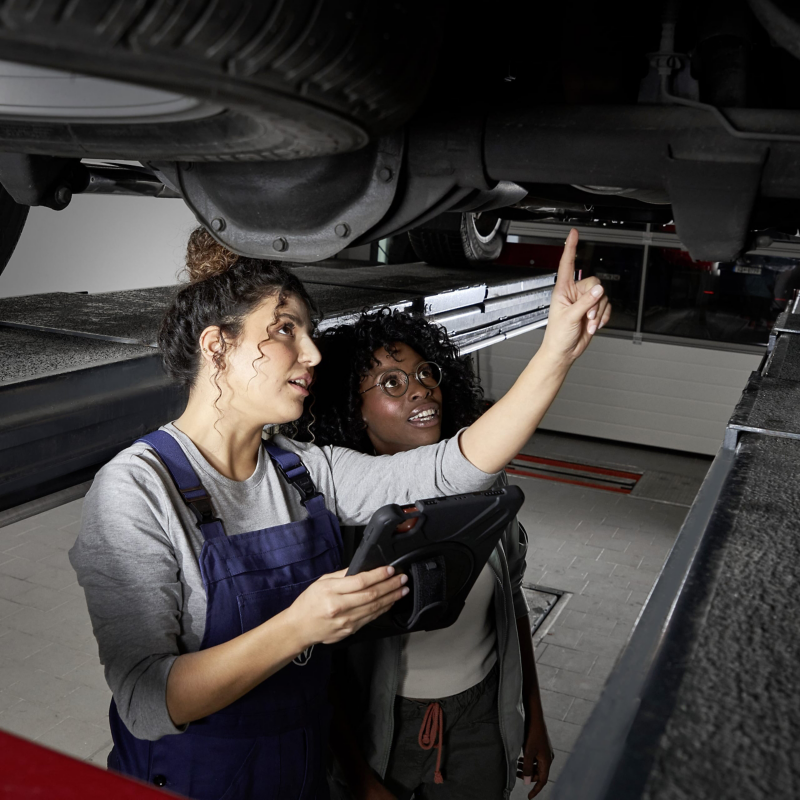 Zwei Frauen stehen unter einem Volkswagen.