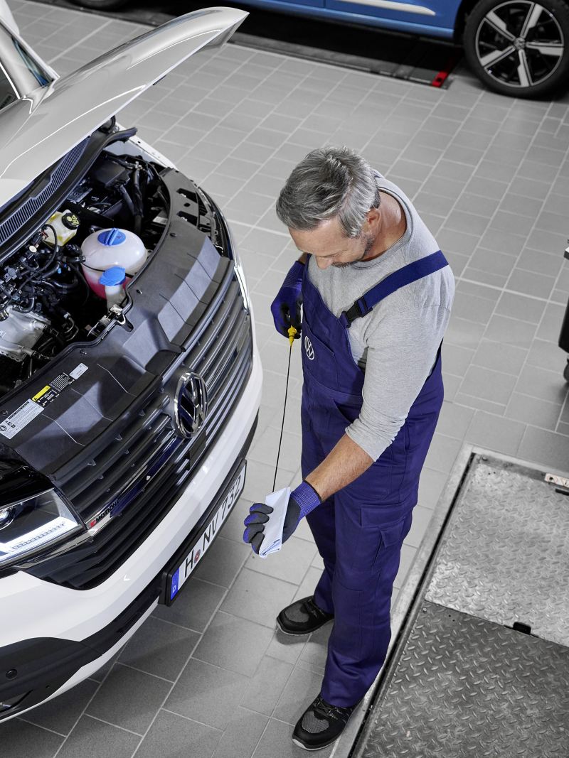 Ein Mechaniker überprüft den Ölstand von einem Volkswagen Fahrzeug.