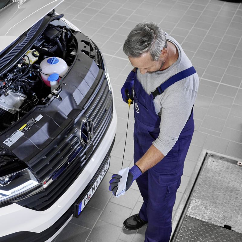 Ein Mechaniker prüft den Ölstand von einem Volkswagen Fahrzeug.
