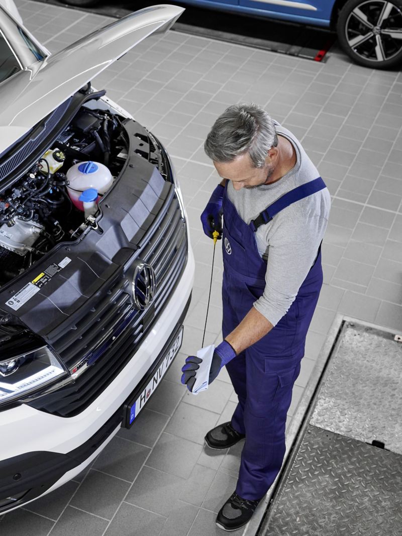 Ein Mechaniker prüft den Ölstand von einem Volkswagen Fahrzeug.