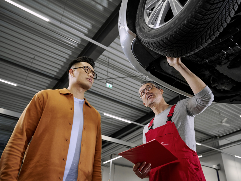 Zwei Männer stehen unter einem Volkswagen.