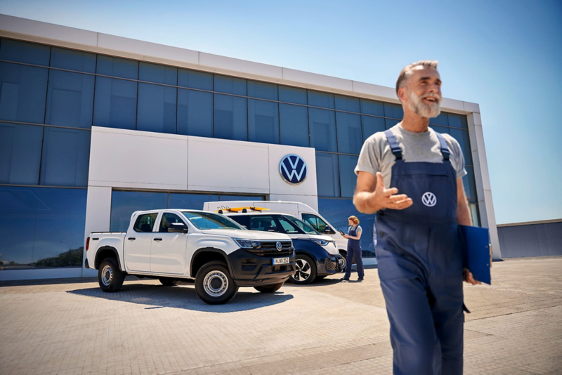 Pracownik idący przed budynkiem serwisu samochodów dostawczych Volkswagen.