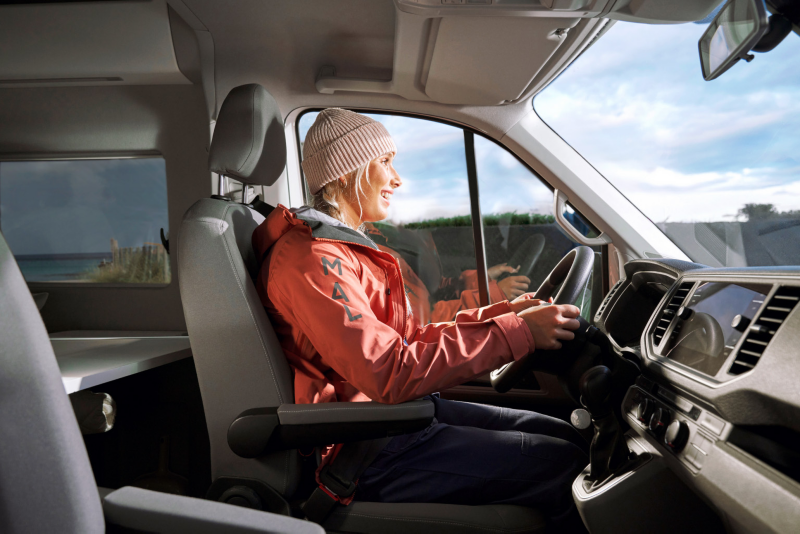 Kobieta w czapce siedzi za kierownicą dostawczego Volkswagena.