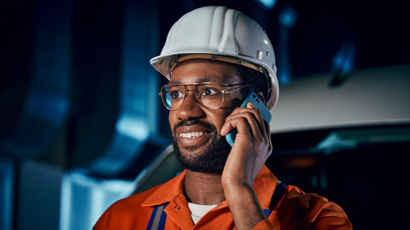 Eine Person Bauarbeiterhelm auf dem Kopf telefoniert.