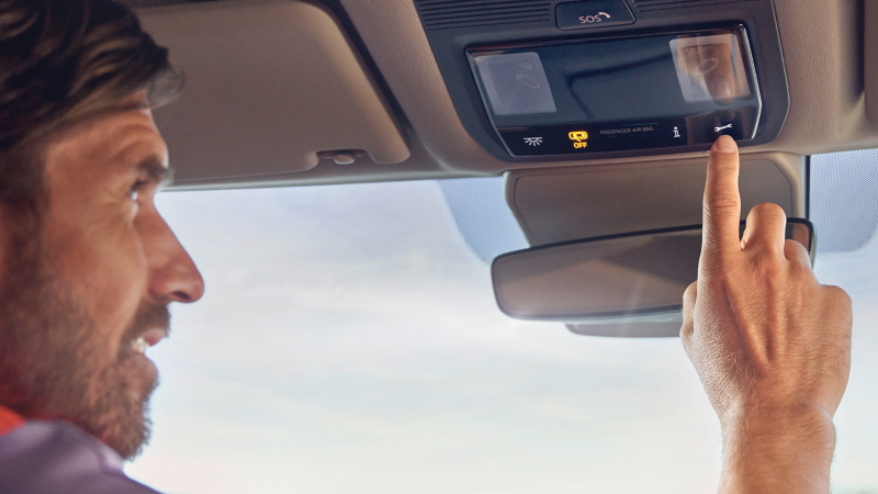 Jemand drückt die Taste Online-Pannenruf in einem Volkswagen Nutzfahrzeug.