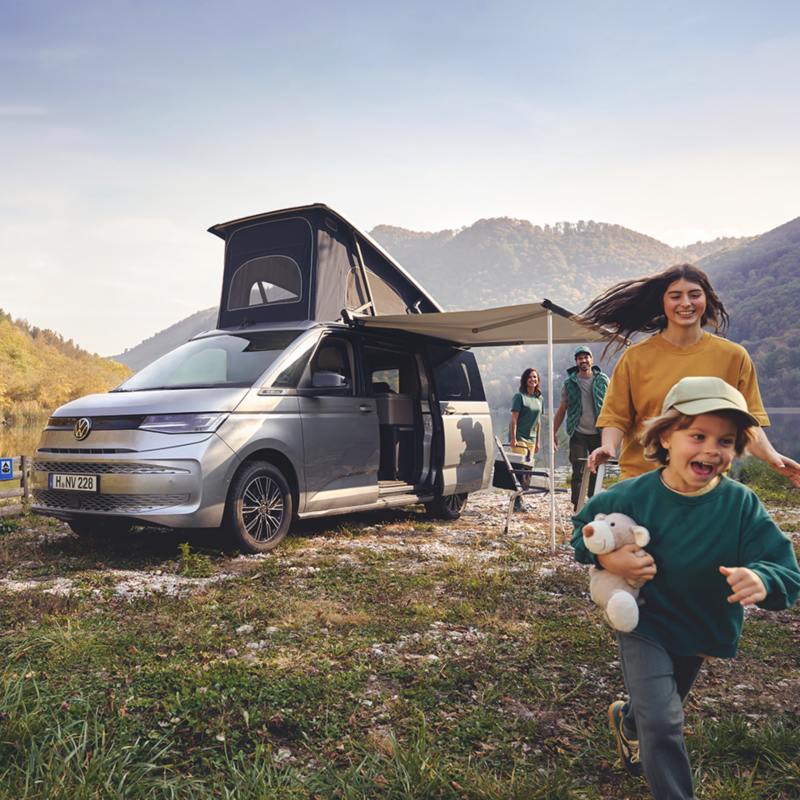 Un hombre y su perro en el bosque, saliendo del VW Nuevo California.