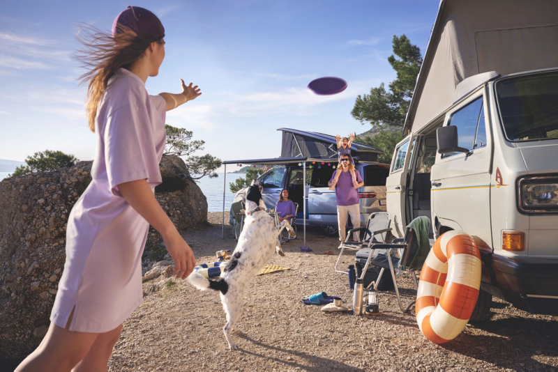 Familia con perro jugando con frisbi fuera de dos campers
