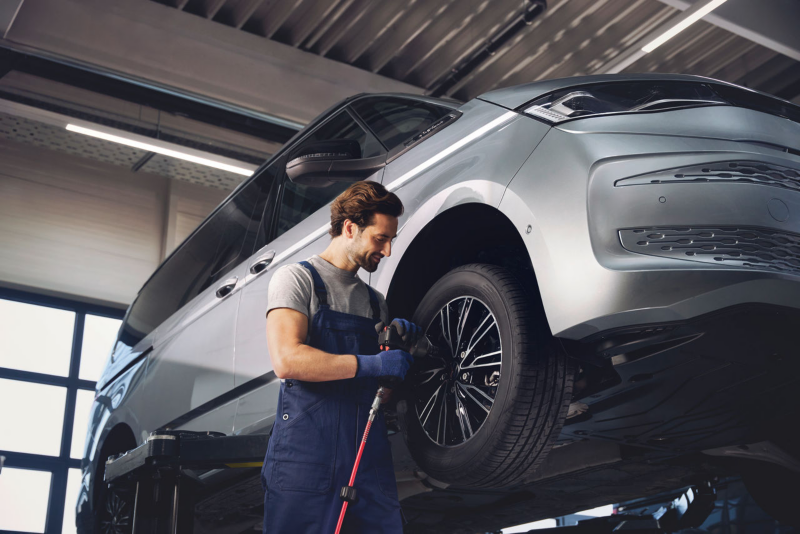 Pracownik serwisu przykręca koło w Volkswagenie Multivanie.