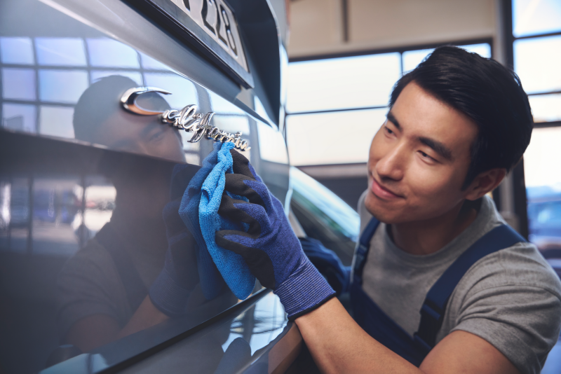 Pracownik serwisu czyści materiałową ścierką tylną klapę dostawczego Volkswagena.
