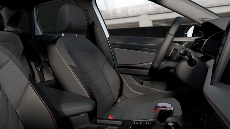 Interior de un auto Volkswagen. Asientos con forro color negro, costuras rojas y volante. 