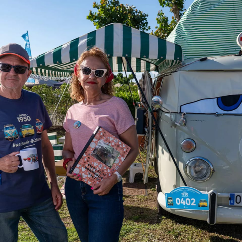 Una pareja con merchandising de Volkswagen junto a una furgo al aire libre