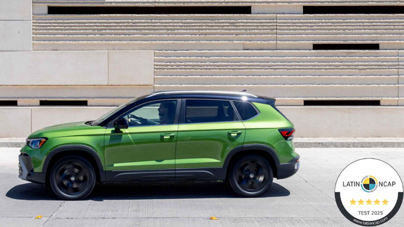 Taos 2026 de color verde y techo negro circula frente a edificio con decorados terracota. 