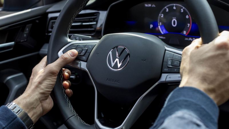 Conductor de Volkswagen toma el volante multifunciones de un auto VW.