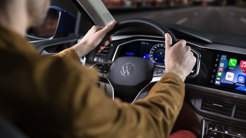 Conductor de Volkswagen Virtus al volante multifunciones del sedán.