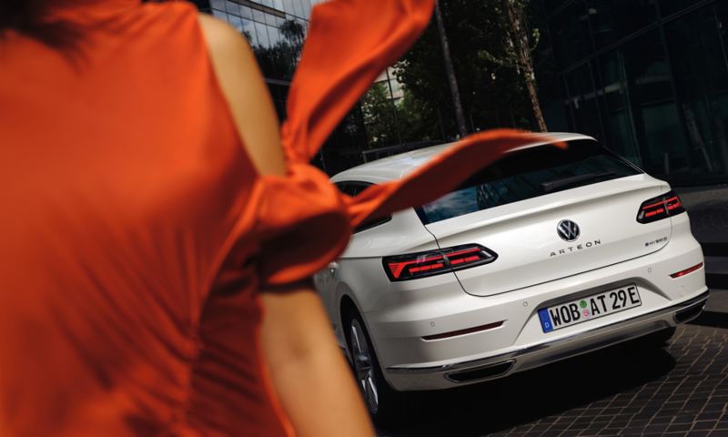 Hvid VW Arteon Shooting Brake eHybrid set bagfra, mens forgrunden består af kvinde