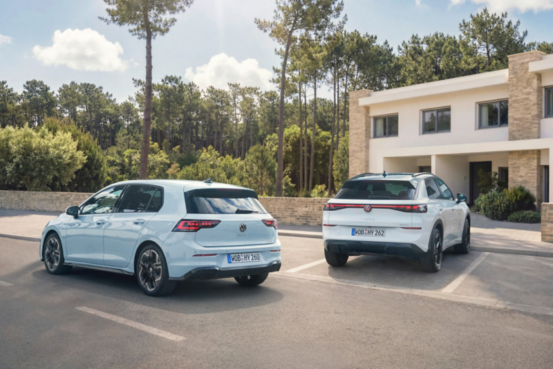 Volkswagen Golf i Volkswagen T-Roc stojące na parkingu przed nowoczesnym budynkiem 