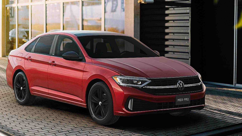 Jetta 2023 de Volkswagen en color rojo, cerca de edificio iluminado por la luz de la tarde.